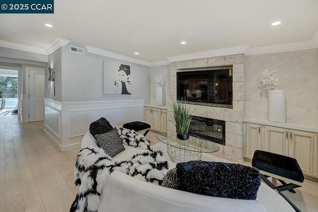 living room with crown molding, a fireplace, and light hardwood / wood-style floors