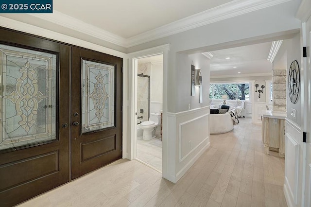 foyer entrance featuring french doors, crown molding, and light hardwood / wood-style flooring