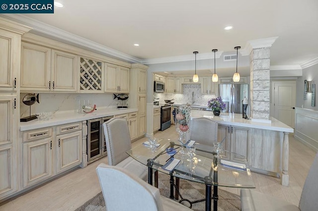 kitchen with hanging light fixtures, cream cabinets, and stainless steel appliances