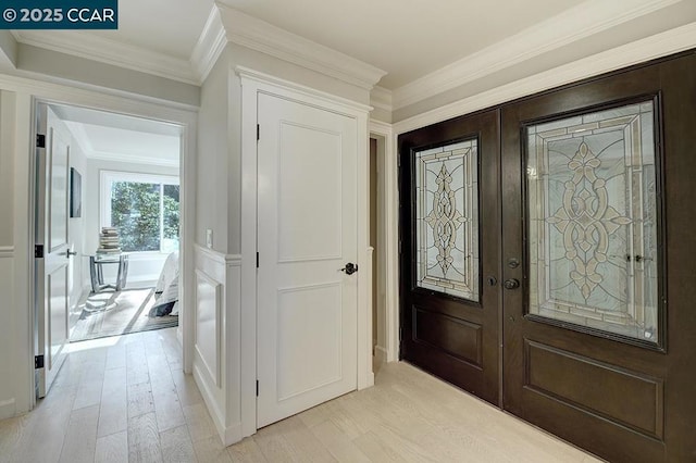 entryway with crown molding, light wood-type flooring, and french doors