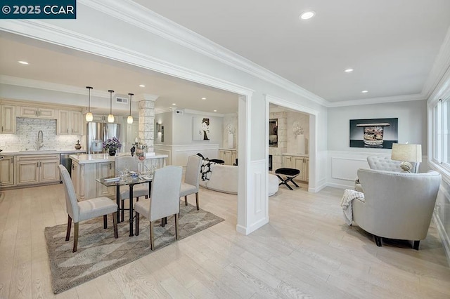 dining room featuring sink, crown molding, and light hardwood / wood-style flooring