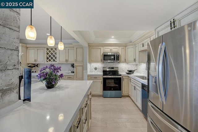 kitchen with a raised ceiling, decorative backsplash, hanging light fixtures, stainless steel appliances, and cream cabinets