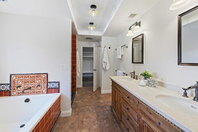 bathroom with a raised ceiling, vanity, and tiled bath