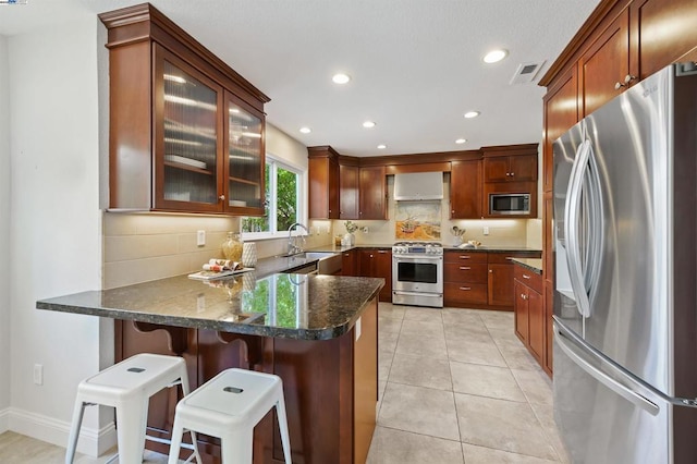 kitchen featuring light tile patterned flooring, sink, a breakfast bar area, kitchen peninsula, and stainless steel appliances