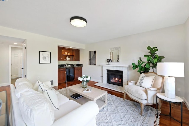 living room featuring wood-type flooring, indoor bar, and a brick fireplace