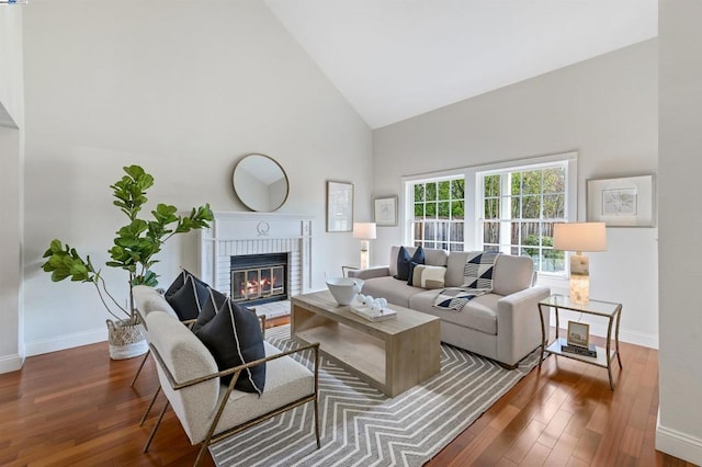 living room with a brick fireplace, dark wood-type flooring, and high vaulted ceiling