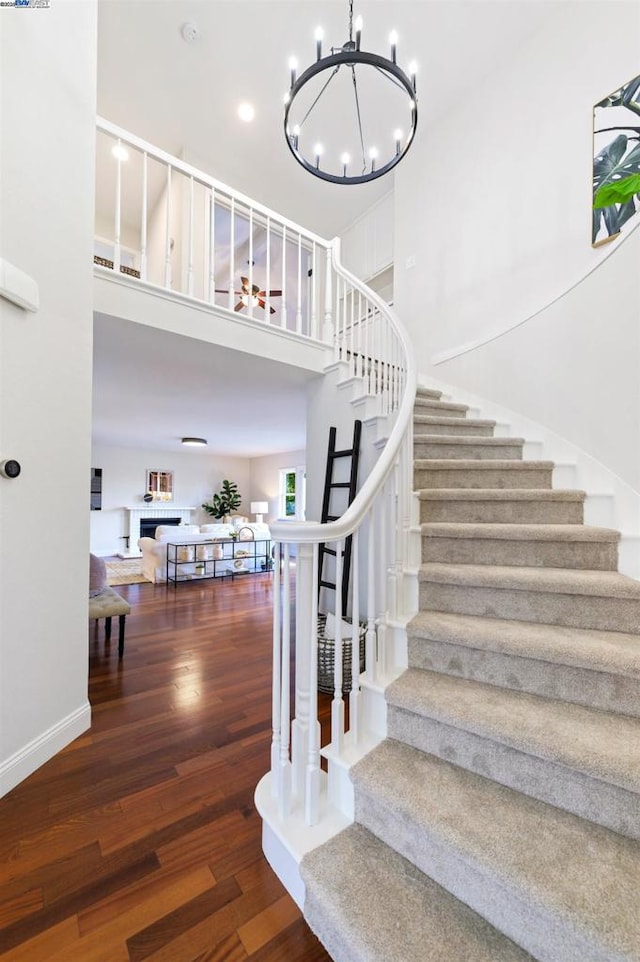 stairway featuring hardwood / wood-style flooring, a chandelier, and a towering ceiling