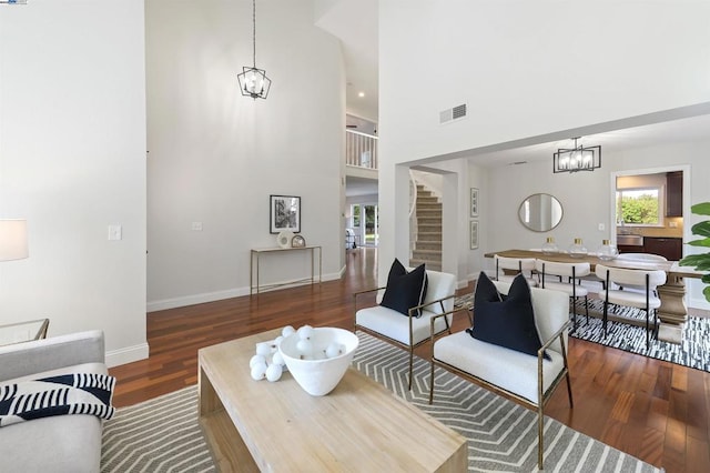 living room featuring a towering ceiling, dark hardwood / wood-style floors, and a chandelier