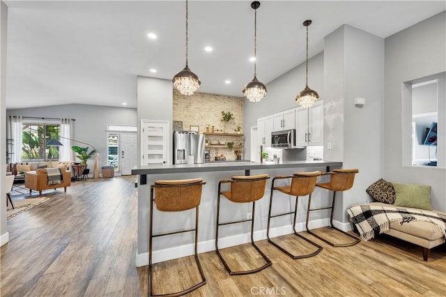 kitchen featuring a peninsula, light wood finished floors, open floor plan, and appliances with stainless steel finishes