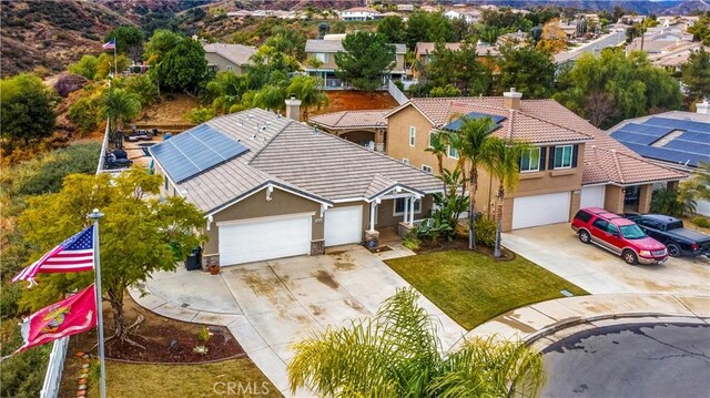 view of front facade featuring a garage, a front yard, and solar panels