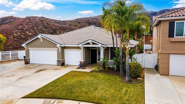 view of front of property with stucco siding, a gate, fence, a mountain view, and a front yard