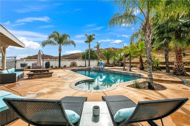 view of swimming pool with a patio, a mountain view, and an outdoor fire pit