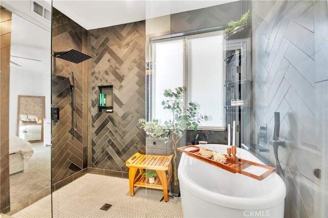 bathroom with plus walk in shower, a healthy amount of sunlight, tile walls, and tile patterned floors