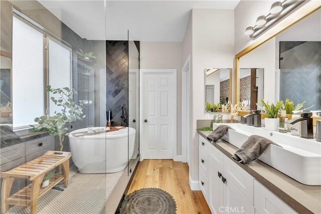 full bathroom with a tile shower, a freestanding bath, a wealth of natural light, and wood finished floors