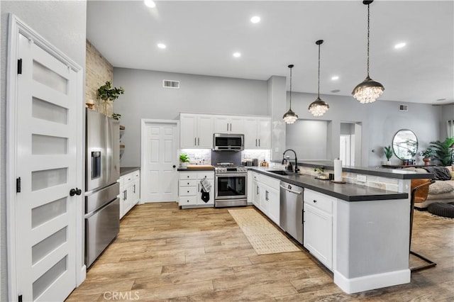 kitchen featuring appliances with stainless steel finishes, white cabinetry, sink, a kitchen breakfast bar, and kitchen peninsula