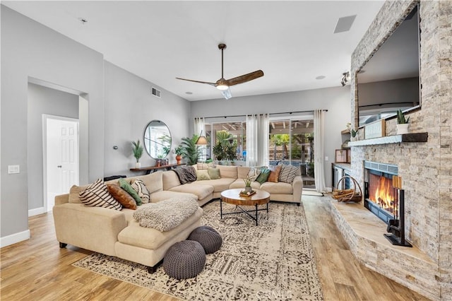 living area with visible vents, light wood-style flooring, a fireplace, and baseboards