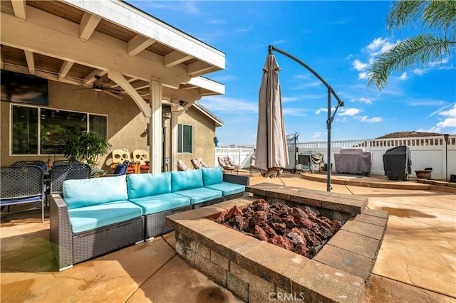 view of patio with area for grilling, an outdoor living space with a fire pit, and ceiling fan