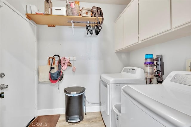 clothes washing area with separate washer and dryer, light wood-style flooring, cabinet space, and baseboards