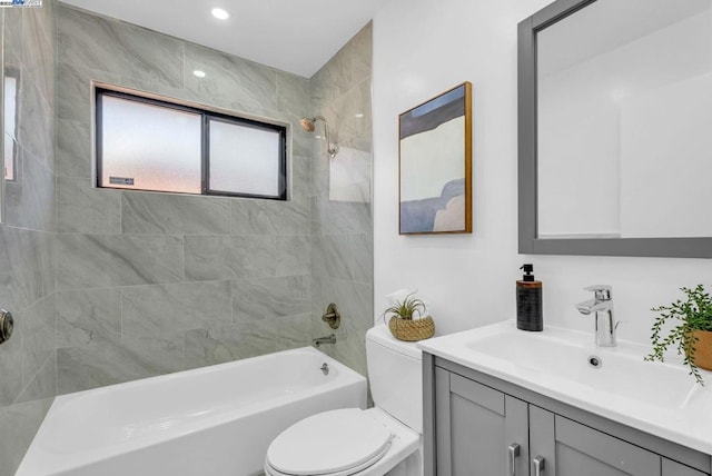 full bathroom with tiled shower / bath, vanity, and toilet