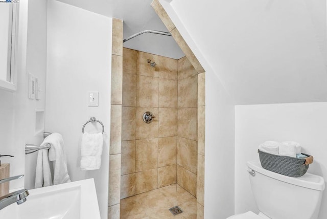 bathroom featuring tiled shower, toilet, and sink