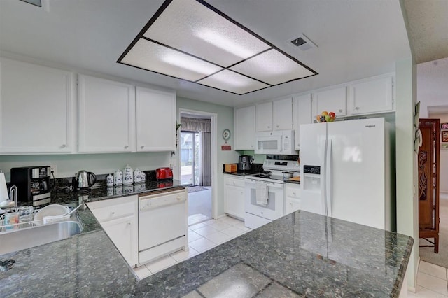 kitchen featuring sink, white appliances, dark stone countertops, white cabinets, and light tile patterned flooring