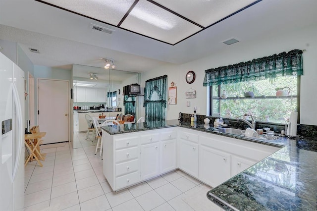 kitchen featuring sink, white cabinetry, dark stone countertops, kitchen peninsula, and white fridge with ice dispenser