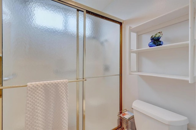 bathroom featuring toilet and a shower with shower door