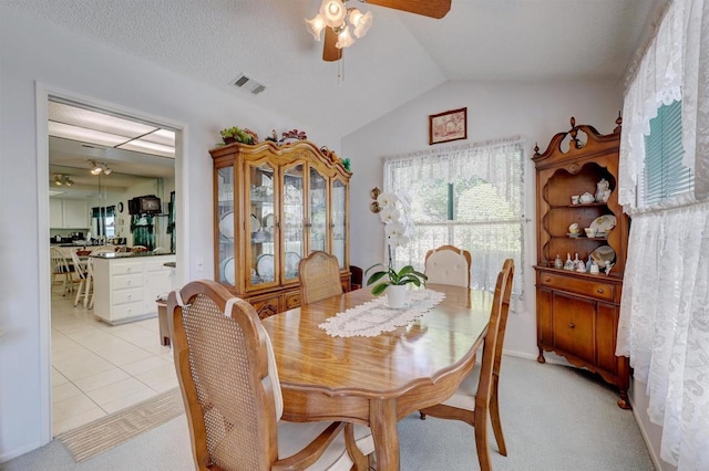 dining area featuring lofted ceiling, ceiling fan, and light tile patterned flooring