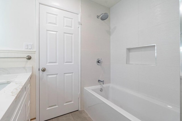 bathroom with tile patterned flooring, tiled shower / bath, and vanity