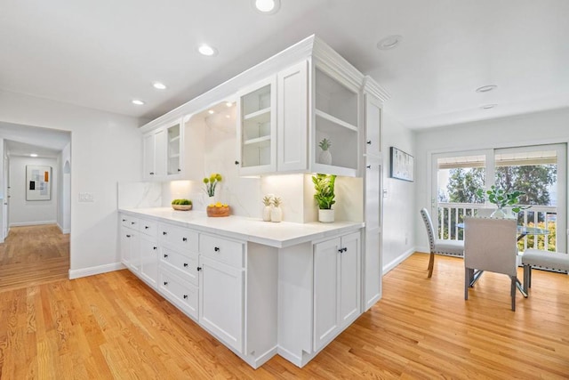 kitchen with decorative backsplash, white cabinets, and light hardwood / wood-style flooring