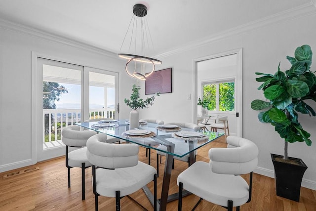 dining room with crown molding and light hardwood / wood-style floors