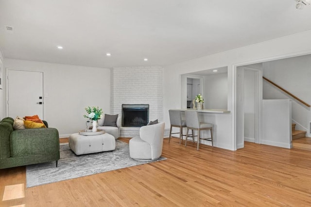 living room featuring light hardwood / wood-style floors and a brick fireplace