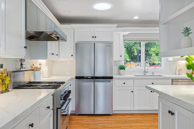 kitchen with range hood, white cabinetry, sink, stainless steel appliances, and light hardwood / wood-style flooring