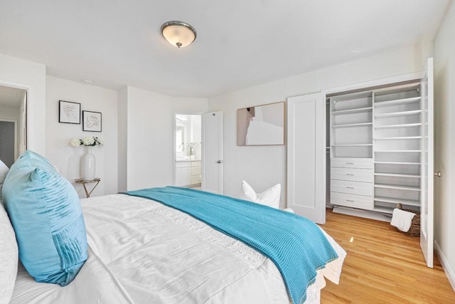 bedroom with hardwood / wood-style flooring, ensuite bath, and a closet