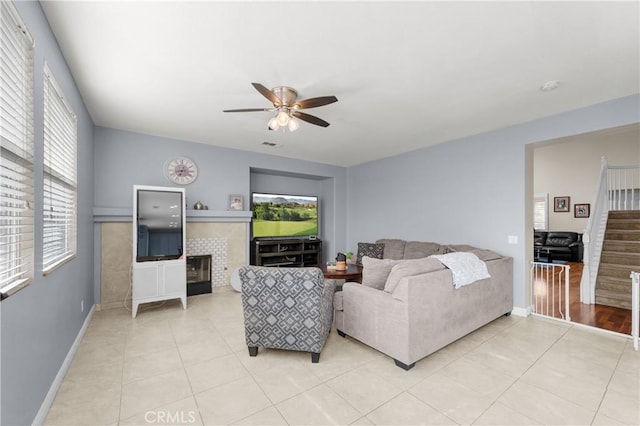 tiled living room featuring ceiling fan and a fireplace