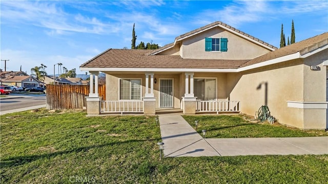 view of front of house with a porch, a front lawn, fence, and stucco siding