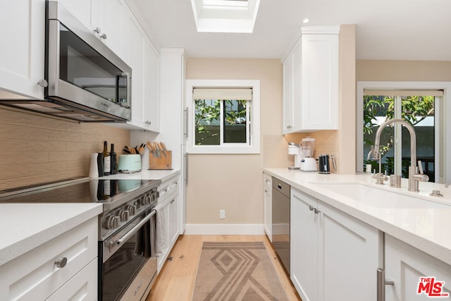 kitchen with white cabinetry, appliances with stainless steel finishes, sink, and a wealth of natural light