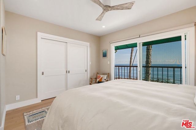 bedroom with ceiling fan, access to exterior, a water view, light hardwood / wood-style floors, and a closet