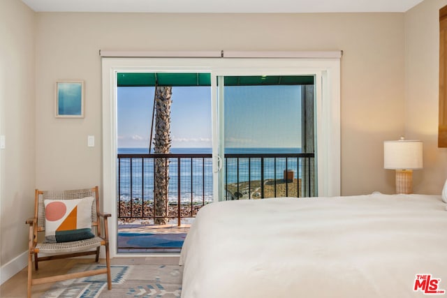 bedroom featuring a water view, access to exterior, and hardwood / wood-style flooring