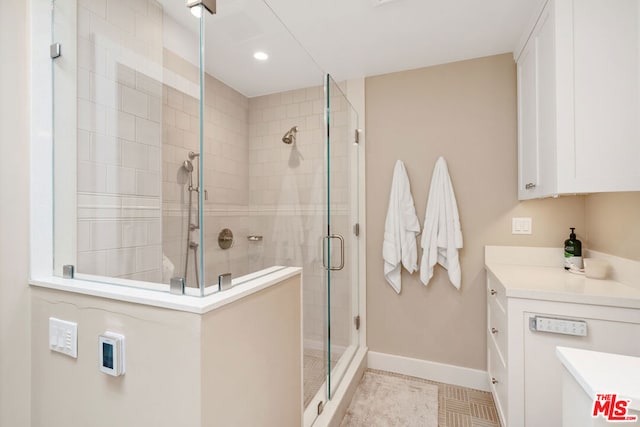 bathroom featuring a shower with door, vanity, and tile patterned floors