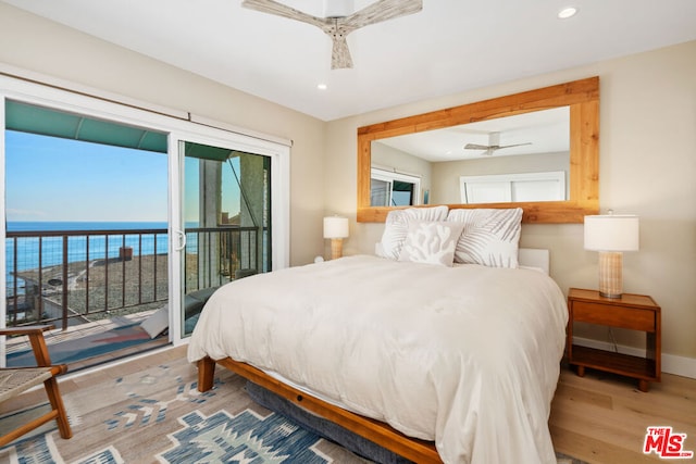 bedroom featuring hardwood / wood-style flooring, a water view, access to exterior, and ceiling fan