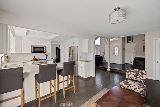 kitchen featuring appliances with stainless steel finishes, tasteful backsplash, white cabinetry, sink, and a kitchen bar