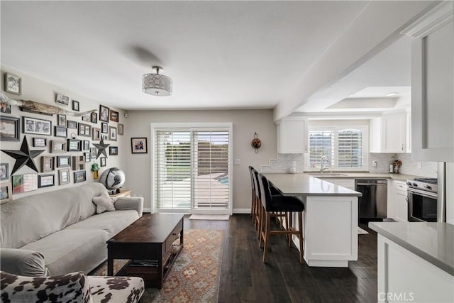 living room featuring plenty of natural light, sink, and dark hardwood / wood-style flooring