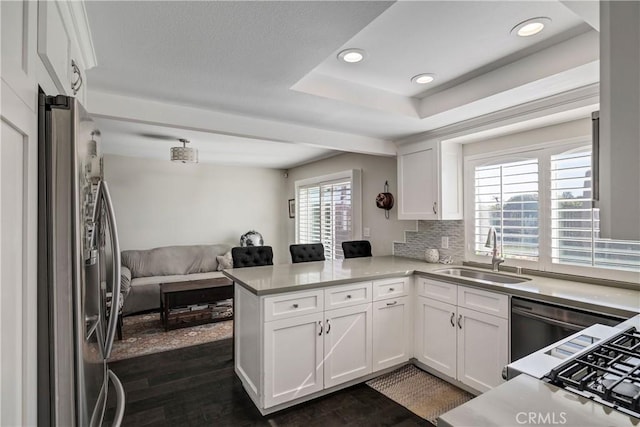 kitchen with stainless steel refrigerator with ice dispenser, sink, dark hardwood / wood-style flooring, kitchen peninsula, and white cabinets