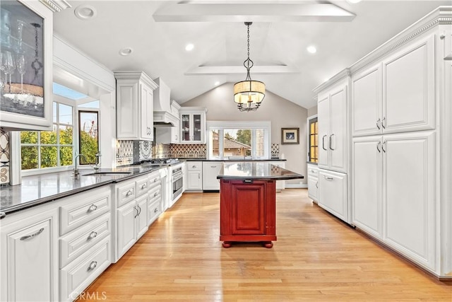 kitchen with pendant lighting, sink, white cabinetry, a center island, and a kitchen bar