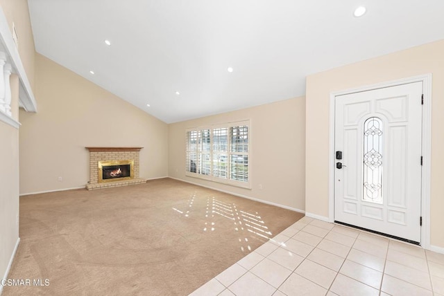 carpeted entrance foyer with a brick fireplace and high vaulted ceiling