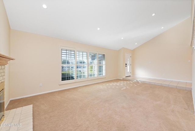 unfurnished living room with high vaulted ceiling, light carpet, and a fireplace