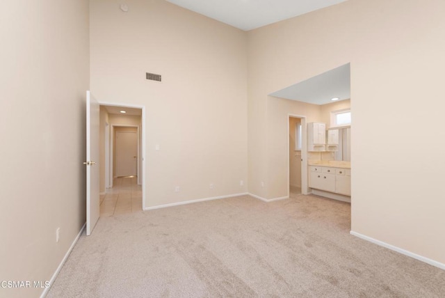 unfurnished room featuring light carpet and a high ceiling