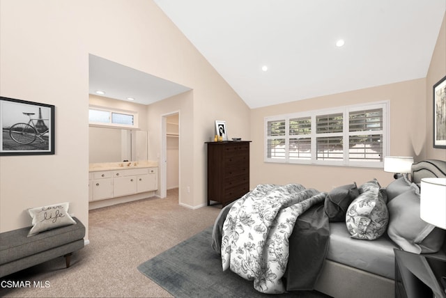 bedroom with a walk in closet, ensuite bathroom, high vaulted ceiling, and light carpet