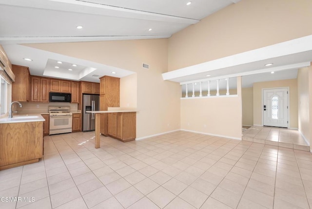 kitchen with sink, light tile patterned floors, stainless steel fridge, gas range gas stove, and high vaulted ceiling